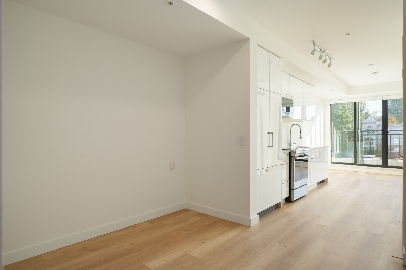 Modern kitchen with white cabinets, stainless steel appliances, and hardwood floors at 2446 Shaughnessy St, Port Coquitlam.