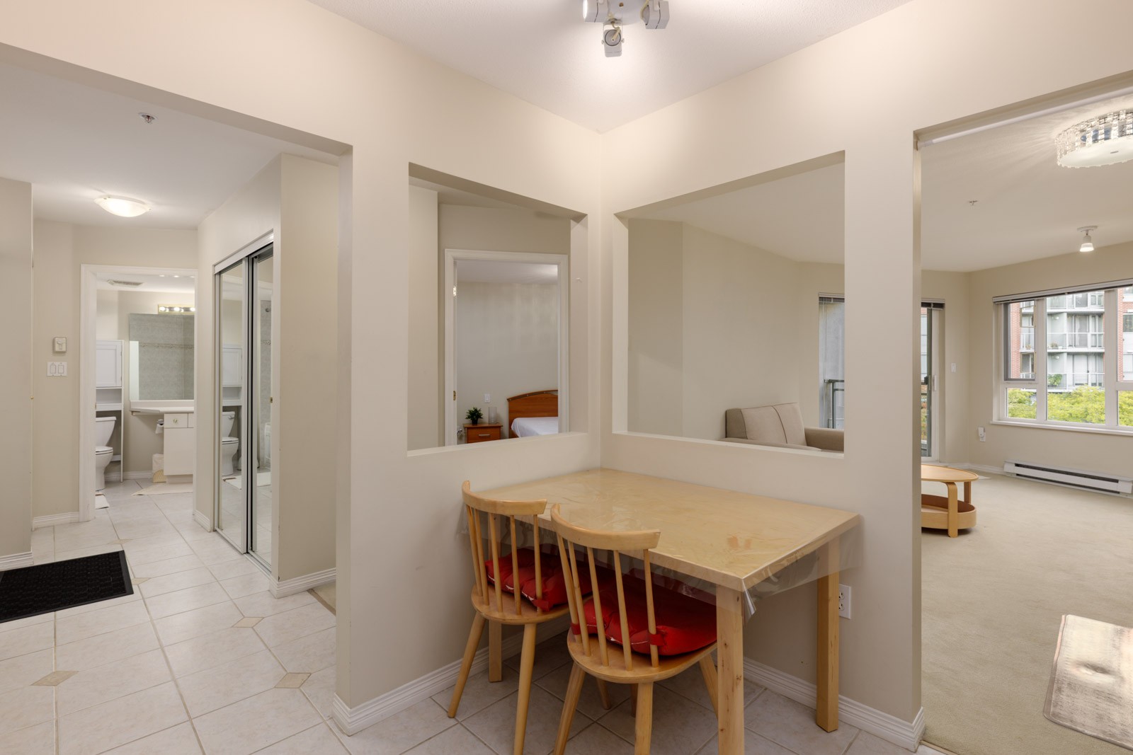 A wooden table and two red-cushioned chairs seen through a wall cutout at 5683 Hampton Pl.