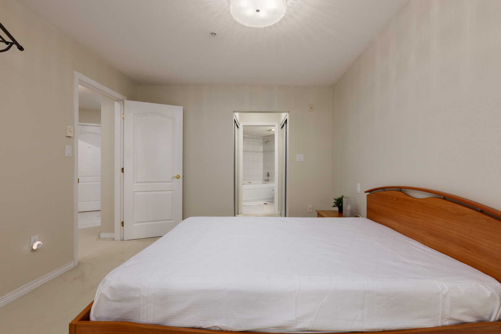 Bedroom with a wood-framed bed and white bedding, featuring a doorway to an adjoining bathroom at 5683 Hampton Pl.