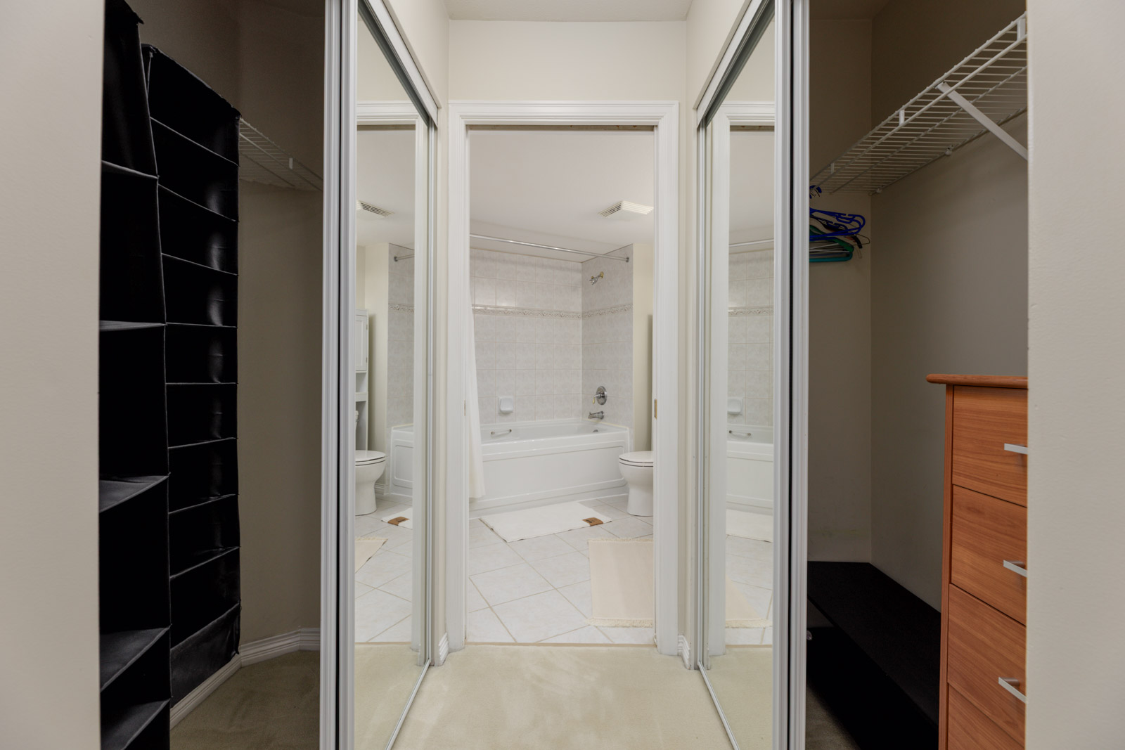 Mirrored closet doors opening into a bathroom with a white tub and toilet at 5683 Hampton Pl, Vancouver.
