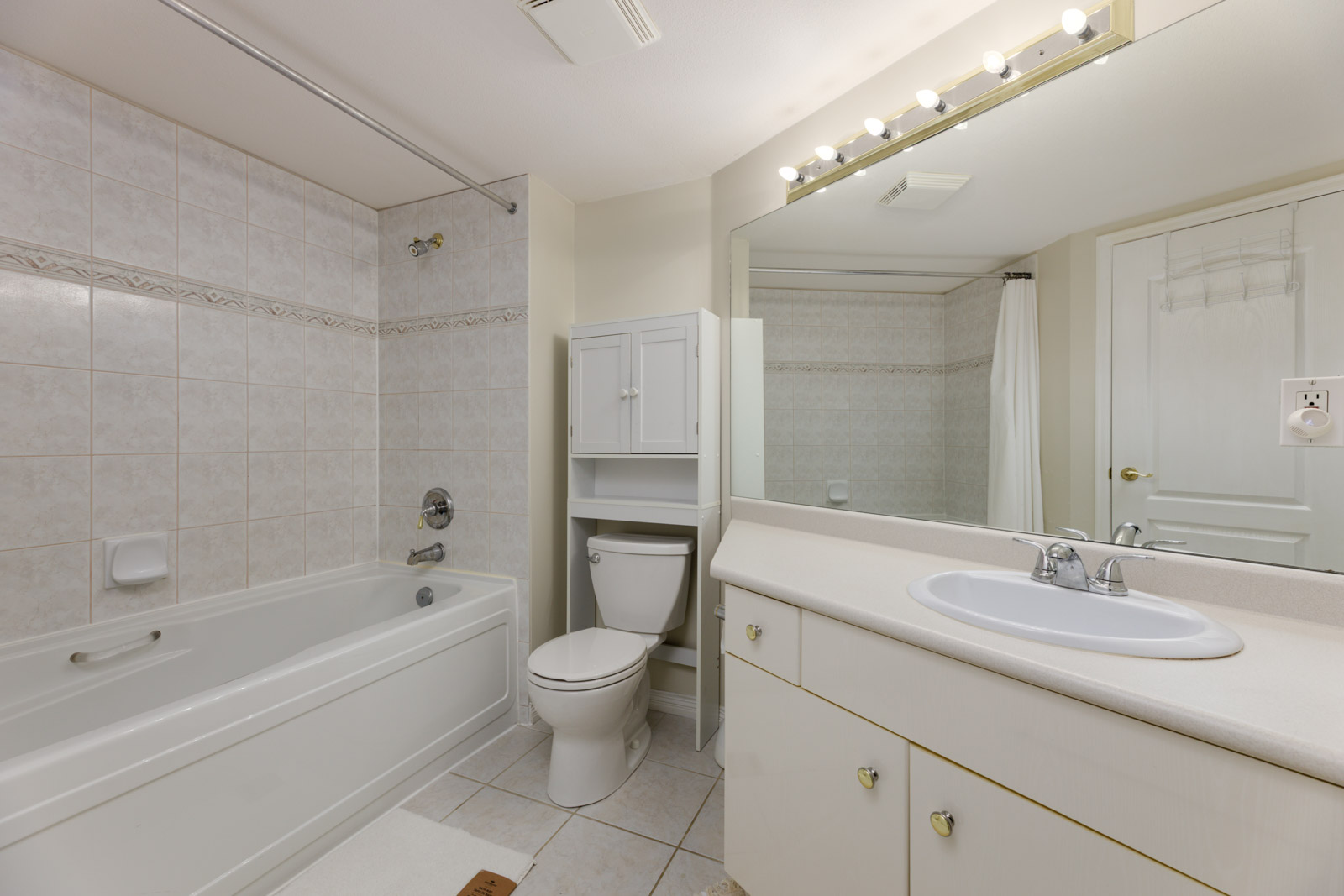 Bathroom at 5683 Hampton Pl featuring a tiled bathtub, a toilet with an upper cabinet, and a vanity with a sink and mirror.