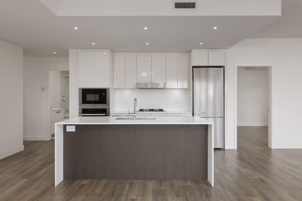 Modern kitchen at 5699 Baillie St featuring white cabinetry, stainless steel appliances, and a dark brown island with a sink.