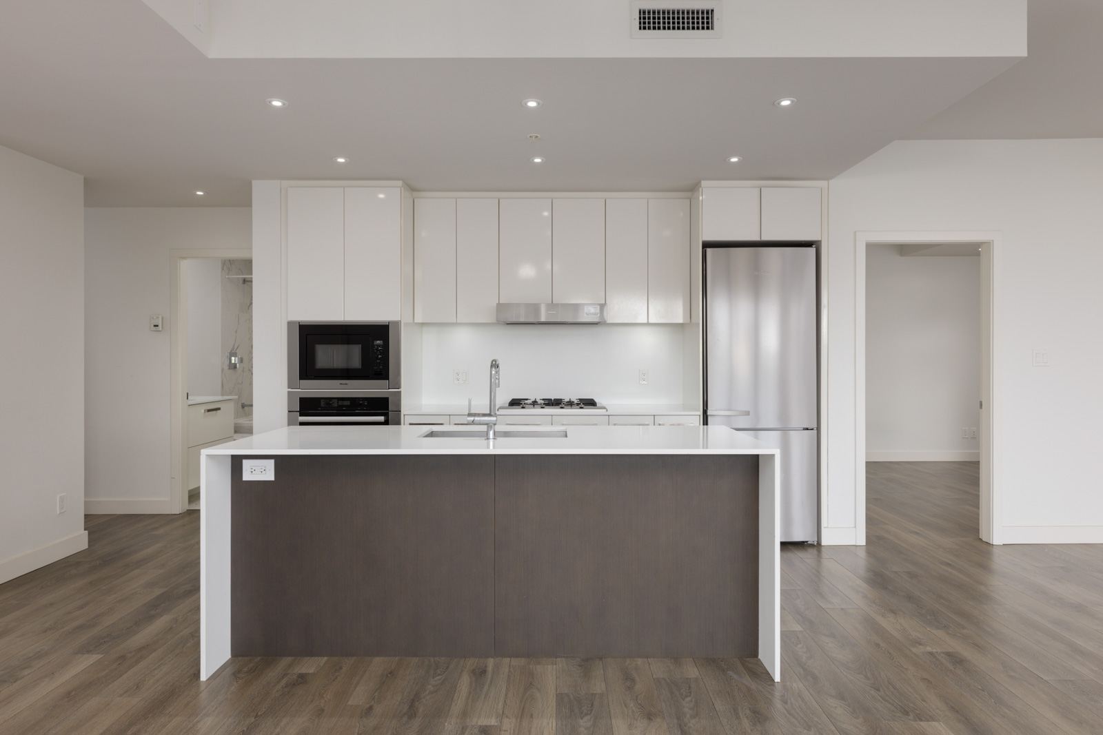Modern kitchen at 5699 Baillie St featuring white cabinetry, stainless steel appliances, and a dark brown island with a sink.