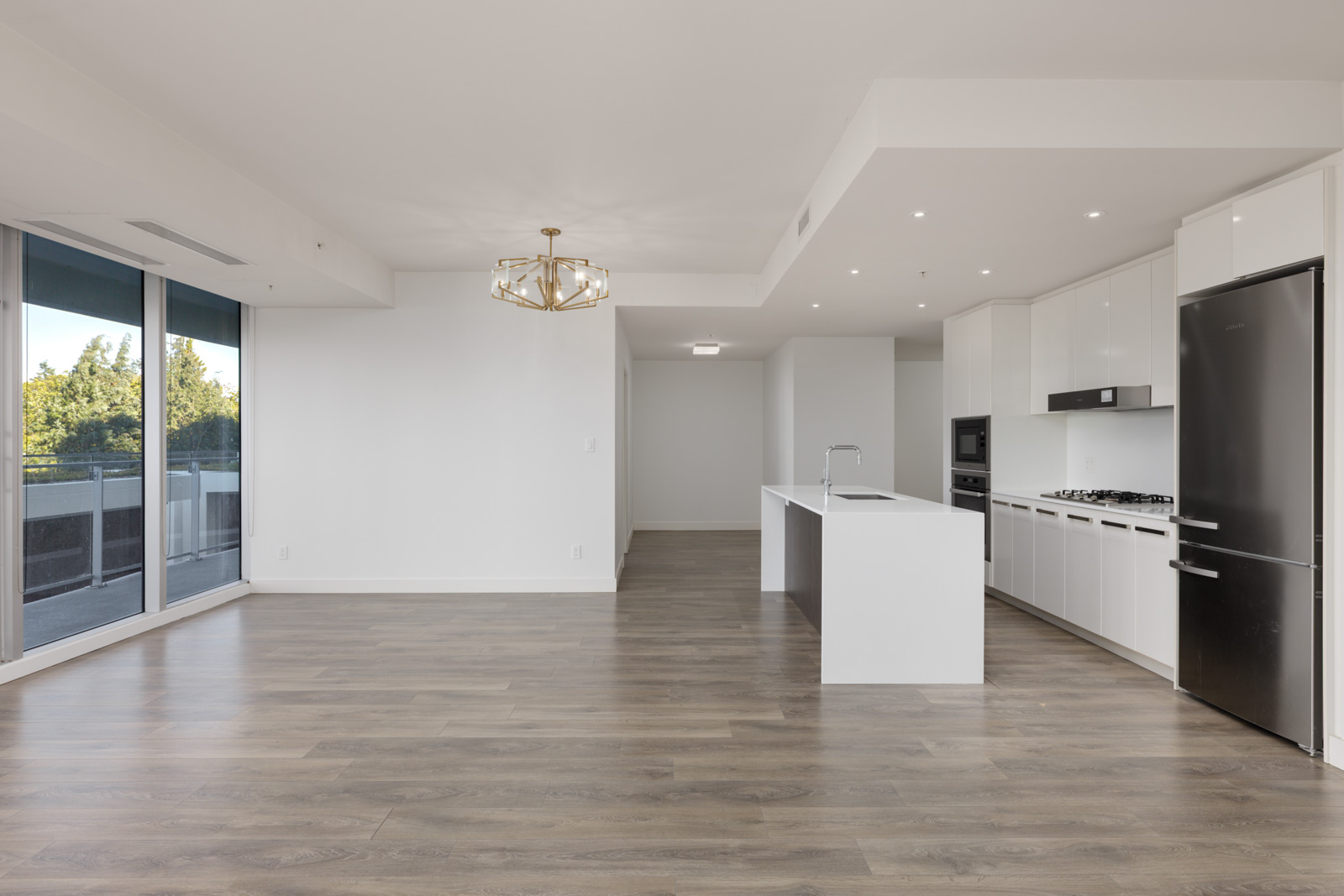 Open-plan kitchen and living area at 5699 Baillie St, with white cabinets, a kitchen island, and a balcony view.