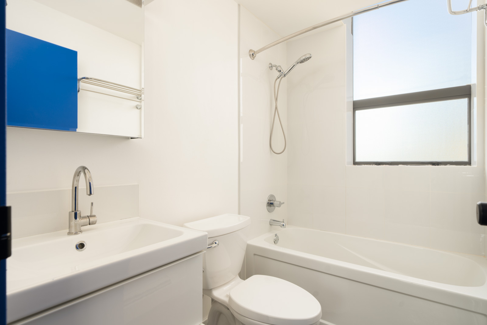 White bathroom at 919 Station Street with a sink, toilet, and a bathtub with a shower head beneath a window.