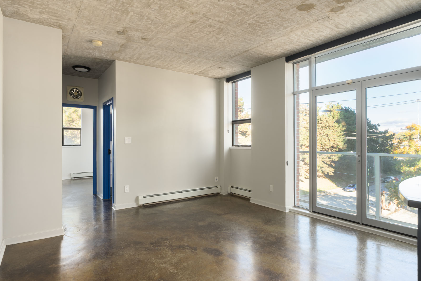 Empty 4th-floor apartment at 919 Station Street featuring concrete floors, a concrete ceiling, and a balcony door.