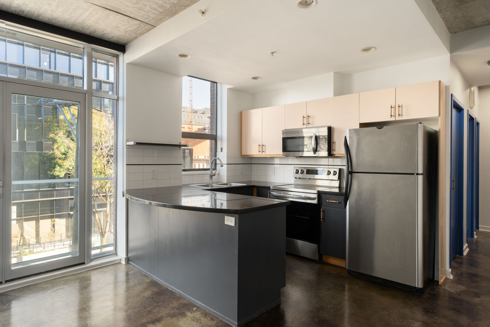 Modern kitchen in a 919 Station Street apartment with a dark gray island, stainless steel appliances, and a balcony door.