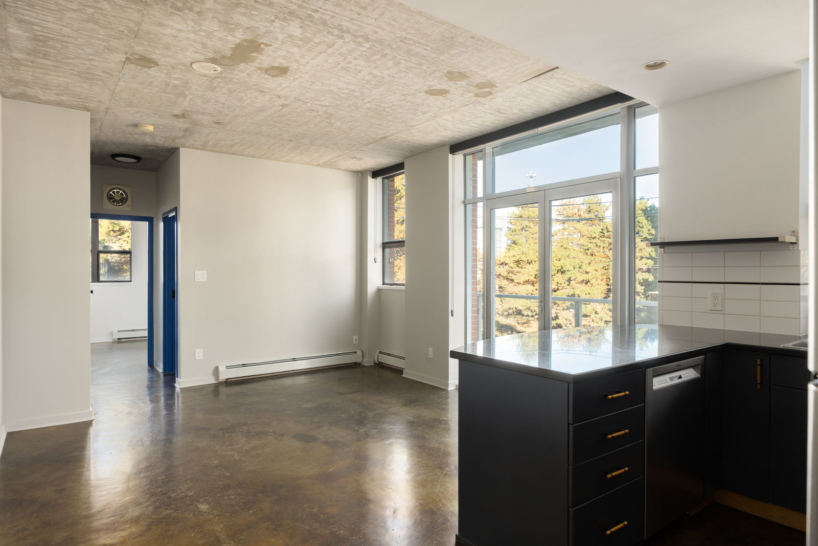 Studio apartment at 919 Station Street featuring a dark kitchen island, concrete ceiling, and a glass balcony door.