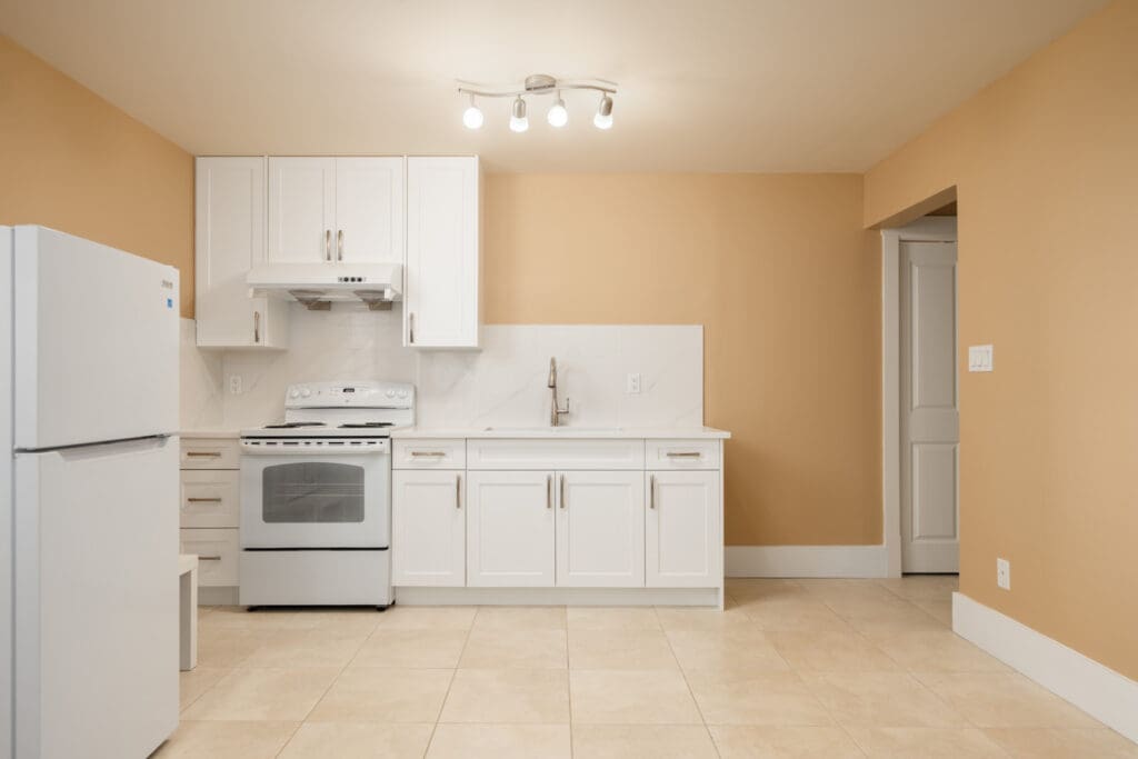 Kitchen with white cabinets, stove, and refrigerator against tan walls in a West 22nd Ave. home.