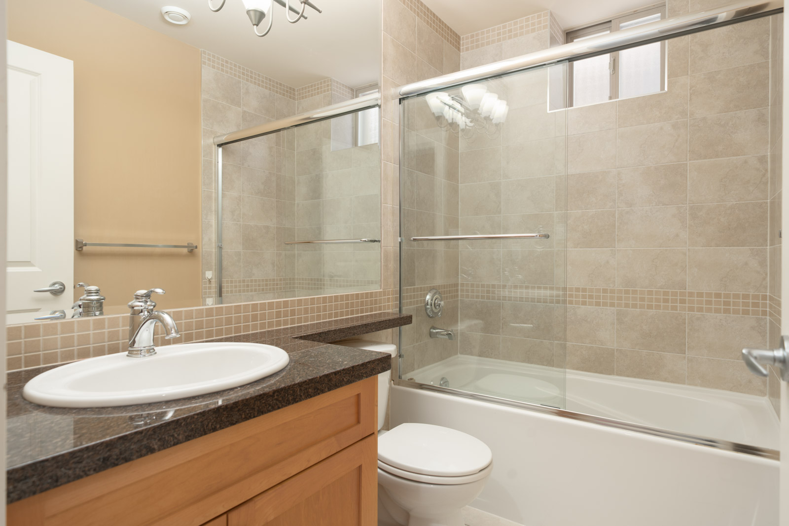 Bathroom in a West 22nd Ave home with a vanity sink, toilet, and glass-enclosed shower/tub combo.