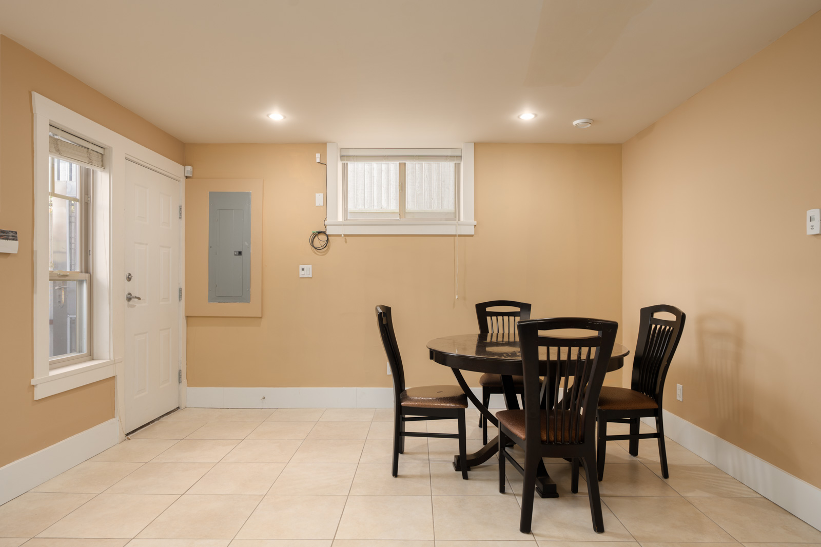 A round dining table with four chairs centered in a room with beige walls and tile floors at Yew St and West 22nd Ave.