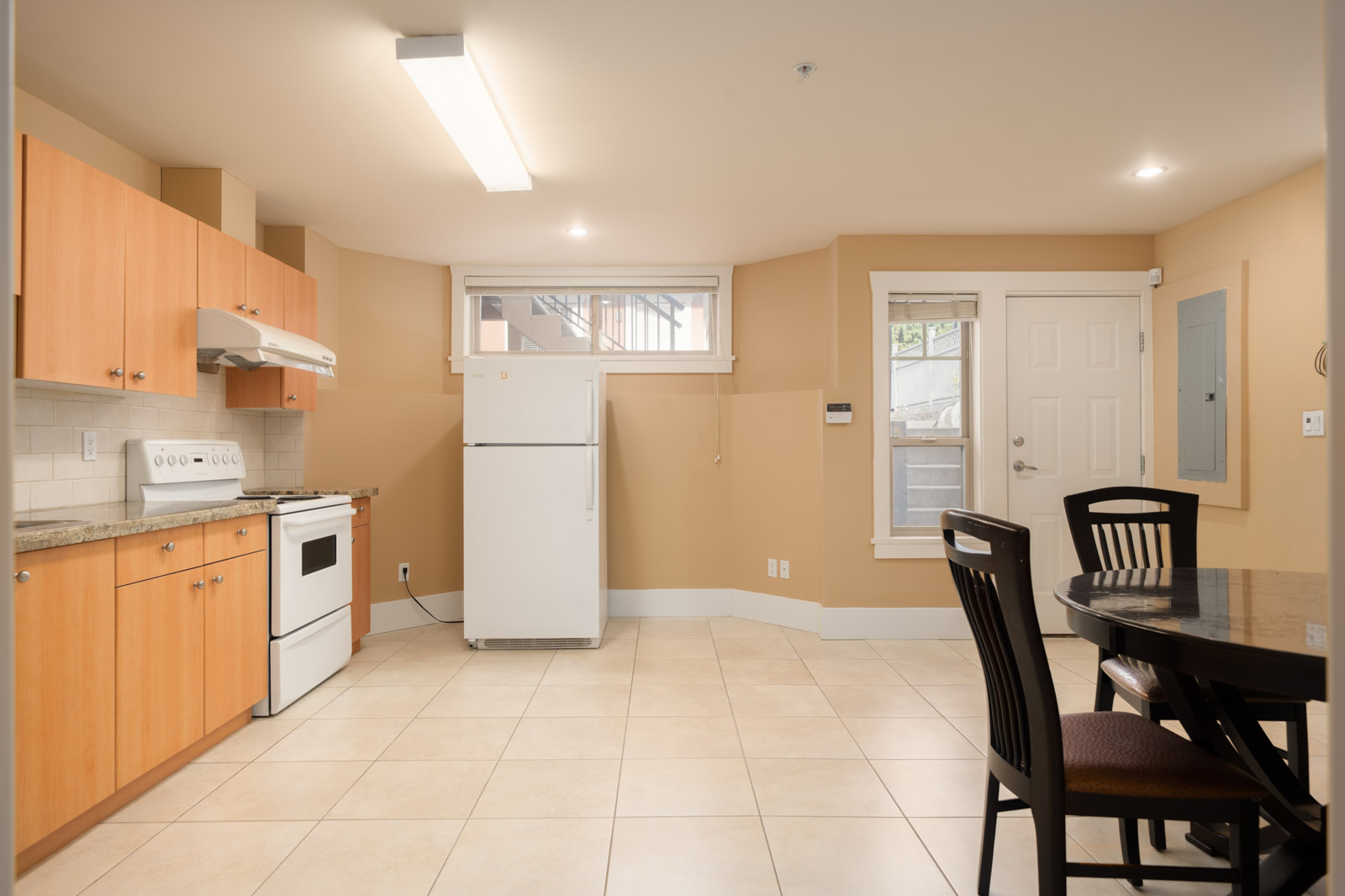 Kitchen on West 22nd Ave featuring light wood cabinets, white appliances, tiled floors, and a small dining set.