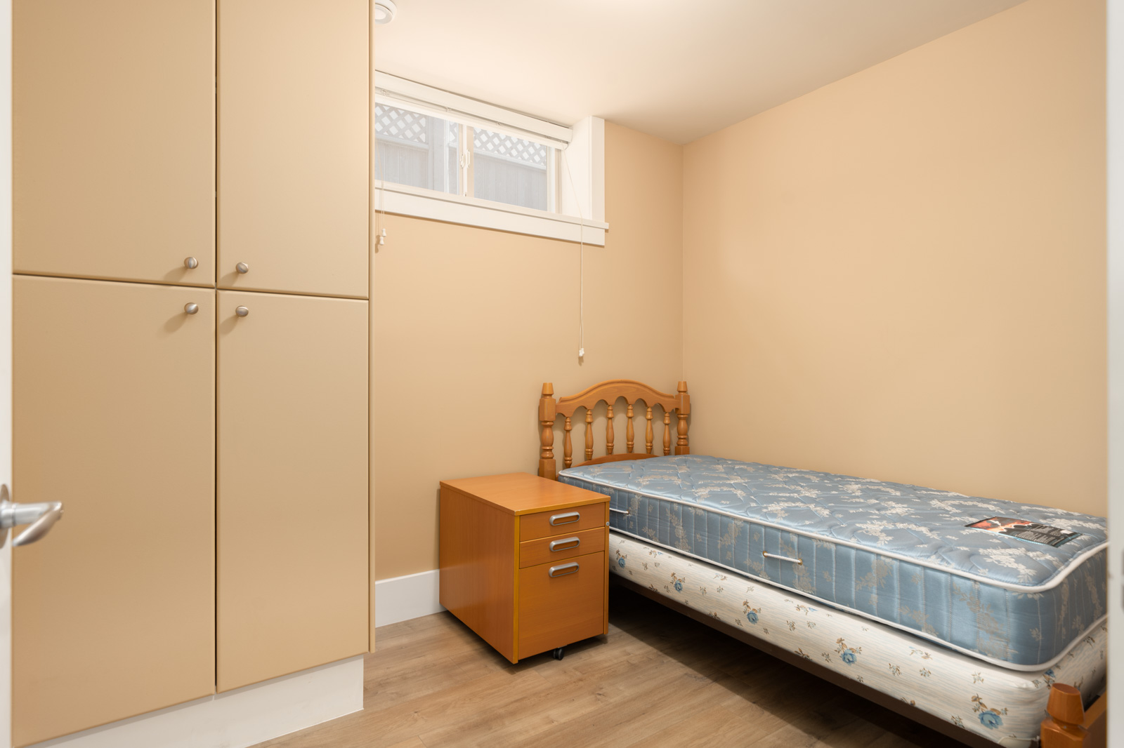 Bedroom on West 22nd Ave featuring a single bed, wooden nightstand, and floor-to-ceiling beige storage cabinet.