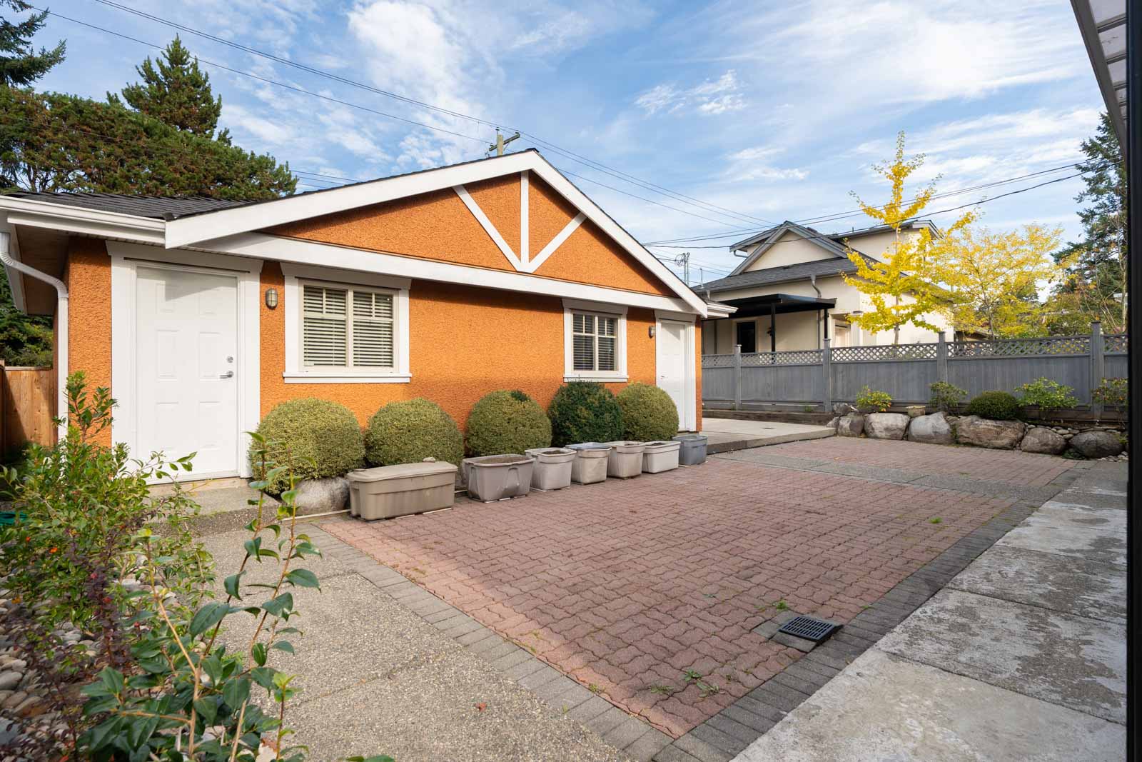 Orange house on West 22nd Ave with a red brick driveway and plastic storage bins against the wall.